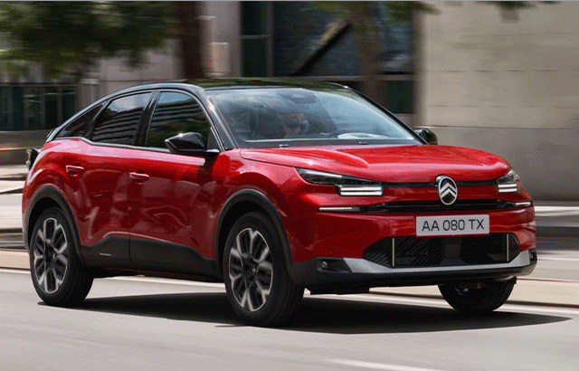 Ein rotes Auto der Marke Citroën fährt auf einer Straße. Die Karosserie ist modern gestaltet mit schwarzen Akzenten und es hat ein französisches Nummernschild mit der Aufschrift „AA 080 TX“. Im Hintergrund sind verschwommene Stadtgebäude zu sehen.